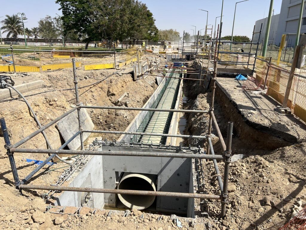 Box culvert and pipe encasement under construction at the Yanbu Entertainment Complex, with scaffold edge protection around the full excavation