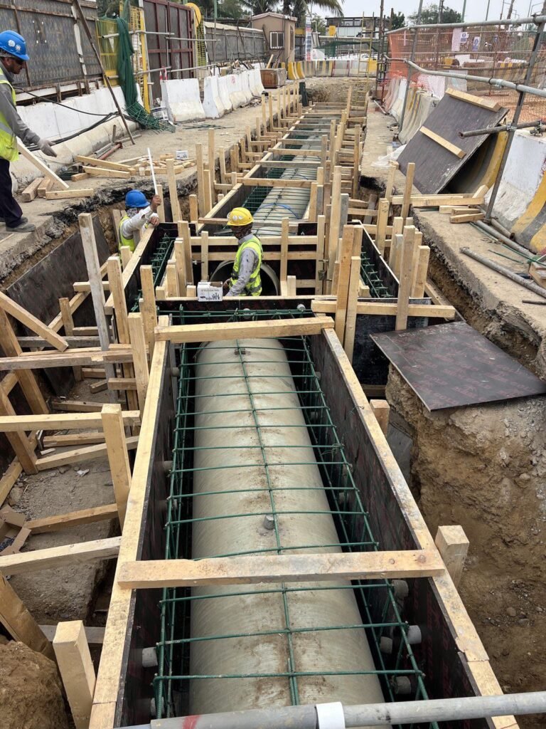 Large bore GRP pipe in its reinforcement cage and timber formwork at the Yanbu Entertainment Complex, ready for the concrete encasement, with the crew working from above the pour